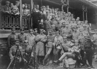 Sierpień 1914. Oddziały Strzelców w „Oleandrach” w Krakowie. Pośrodku widoczna kobieta z szablą i rewolwerem w kaburze, z prawej chłopiec w mundurku skautowskim. Widoczne również karabiny Mannlicher wz. 1890 ustawione w kozły
